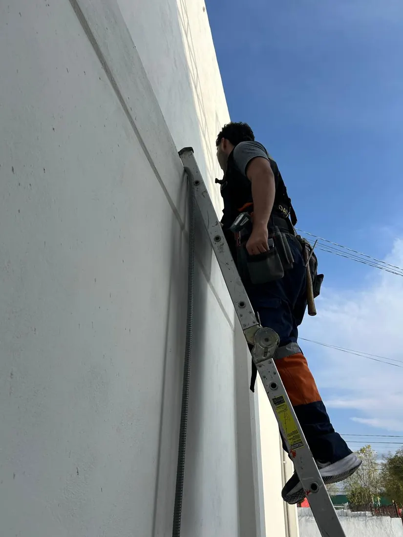Técnico de DAVALTECH instalando tubería en un muro exterior