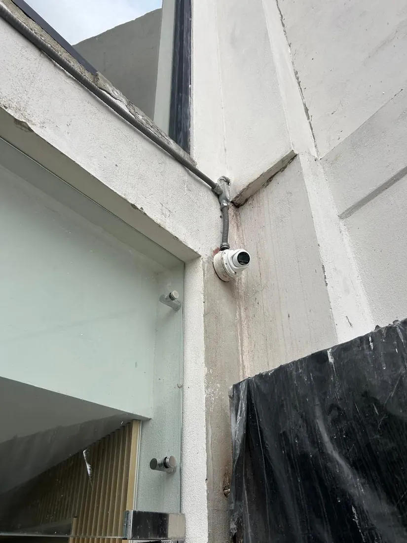 Cámara domo instalada en la esquina exterior de un edificio, con su canalización