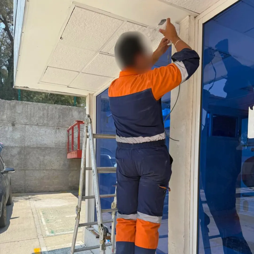 Técnico de DAVALTECH montando una cámara domo bajo la marquesina de un acceso