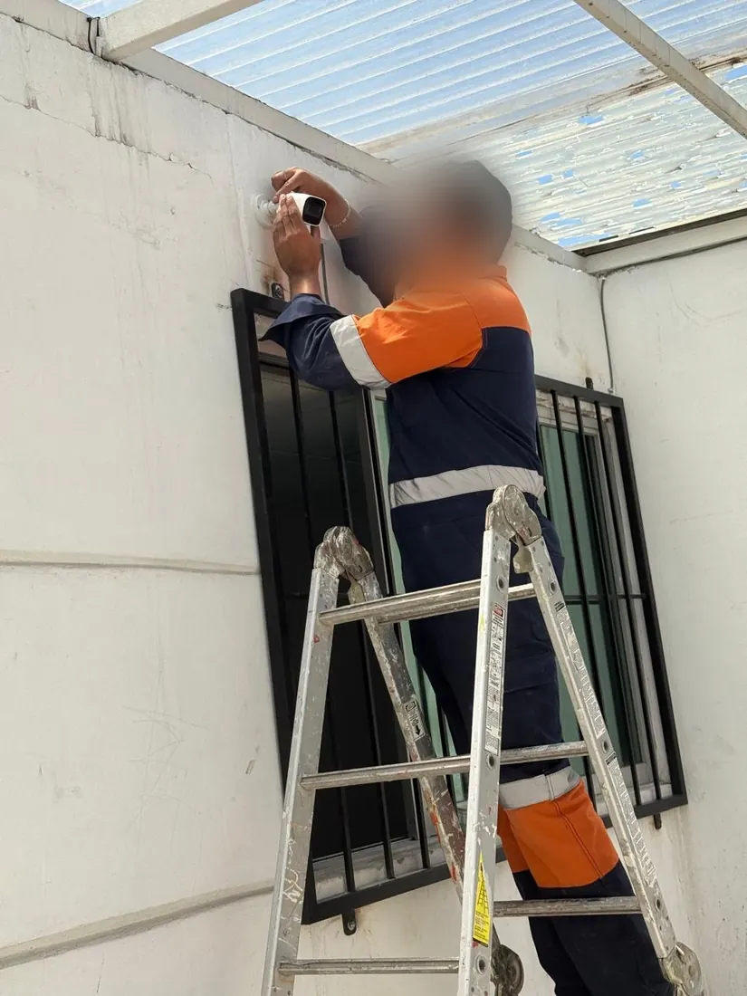 Técnico de DAVALTECH instalando una cámara en un muro exterior desde una escalera
